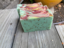 Green soap bar embedded with dried mint leaves, too swirled with burgundy and yellow mica