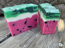 Watermelon soap bar, pink/red layer on the bottom with black specks; white middle layer and light and dark green top layer with glitter sprinkled on top. Simon Sudz stamped on the side.
