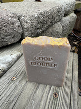 Light brown/grey soap bar with “Good Trouble” stamped on the front