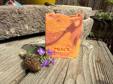 Orange gradient colored soap bar with the word “Peace” stamped on the front 