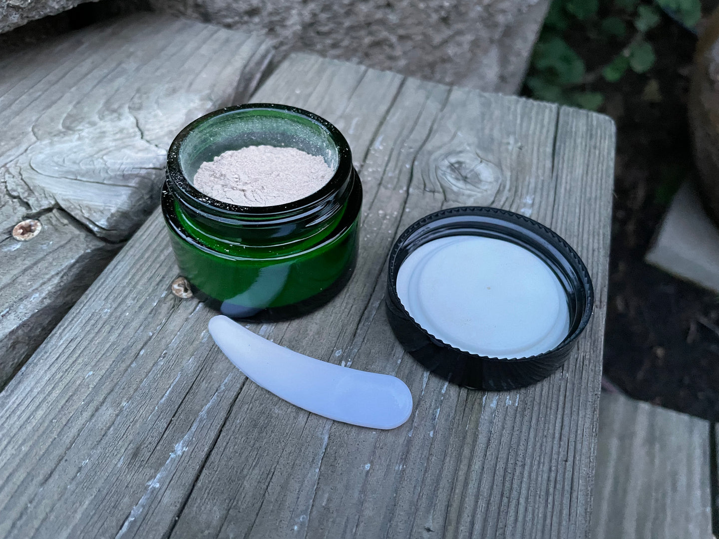an open jar of shea butter with white lid on top of picnic table